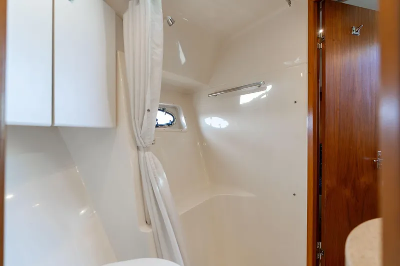 Slide: The Image of 1998 Tiara Yachts 3500 Express bathroom with white interior and wooden door. - 25