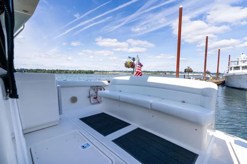Slide: The Image of 1998 Tiara Yachts 3500 Express with white seating, docked by a scenic waterfront. - 42