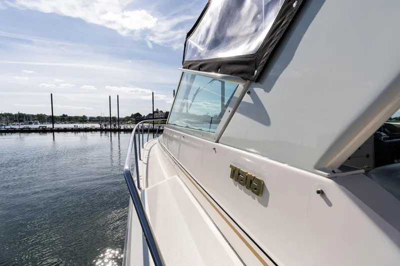 Slide: The Image of 1998 Tiara Yachts 3500 Express docked at a serene marina under a clear sky. - 47