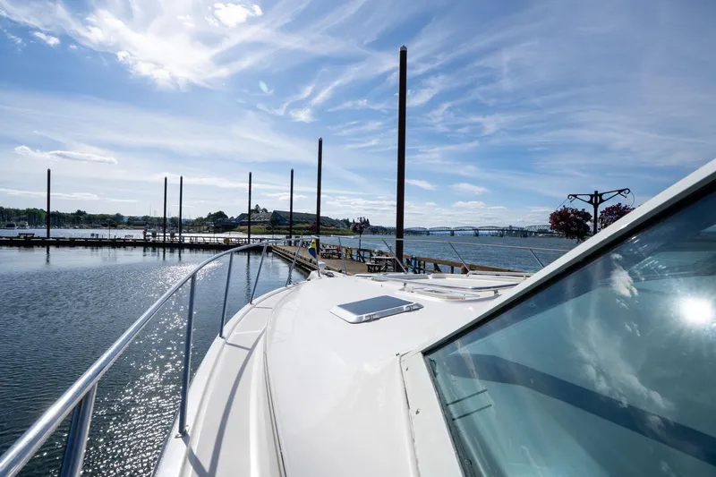 Slide: The Image of 1998 Tiara Yachts 3500 Express docked at a scenic marina under a clear blue sky. - 48