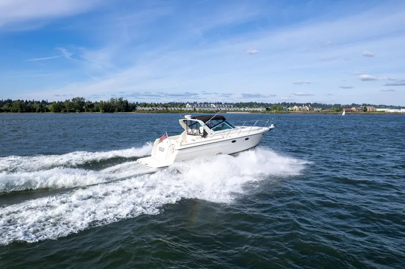 Slide: The Image of 1998 Tiara Yachts 3500 Express cruising on open water under a clear blue sky. - 54