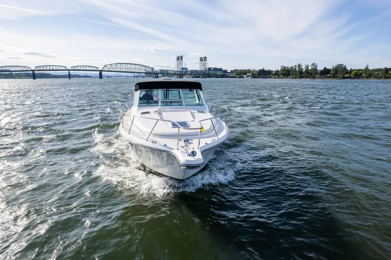 Slide: The Image of 1998 Tiara Yachts 3500 Express cruising on a river with a bridge in the background. - 58