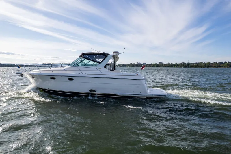 Slide: The Image of 1998 Tiara Yachts 3500 Express cruising on a scenic lake under a clear sky. - 60