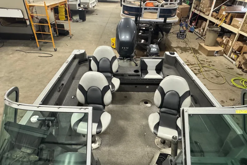 Slide: The Image of 2013 Alumacraft Competitor 175 Sport boat interior with seating and motor in a workshop. - 17