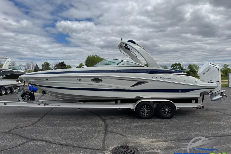 The Image of 2025 Crownline 290 XSS boat on trailer, parked outdoors under cloudy sky. - 0