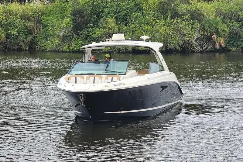 Slide: The Image of 2019 Sea Ray SLX 400 Outboard cruising on a calm river with lush greenery. - 3