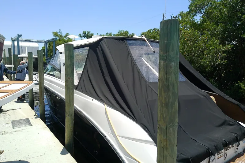 Slide: The Image of 2019 Sea Ray SLX 400 Outboard docked with black cover, surrounded by wooden posts. - 4