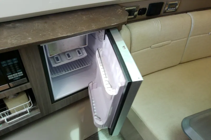 Slide: The Image of Interior of 2019 Sea Ray SLX 400 Outboard with open mini fridge and beige seating. - 45