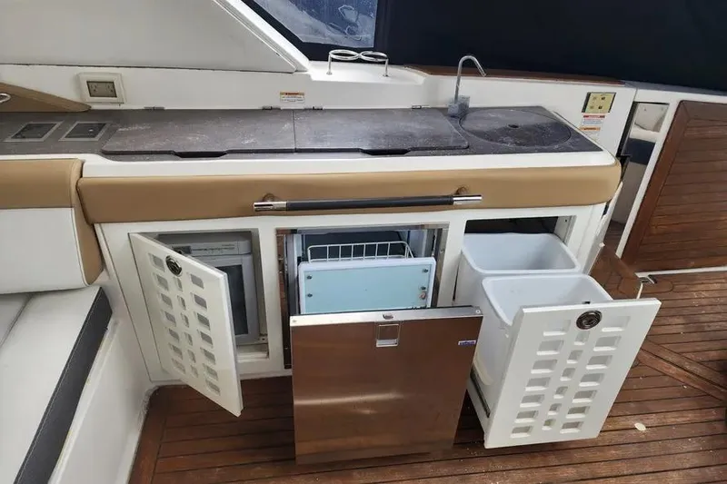 Slide: The Image of 2019 Sea Ray SLX 400 Outboard galley with open storage and appliances on teak flooring. - 7