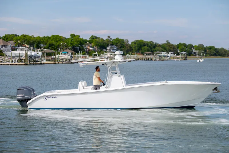 Slide: The Image of 2013 Yellowfin 32 Offshore boat cruising on a calm waterway with scenic background. - 1