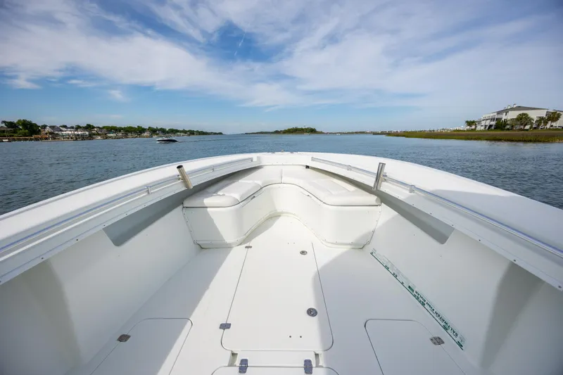 Slide: The Image of 2013 Yellowfin 32 Offshore boat on calm water, featuring spacious deck and seating. - 10