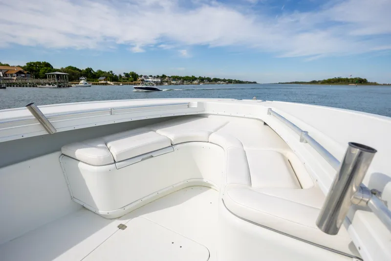 Slide: The Image of 2013 Yellowfin 32 Offshore boat interior with white seating, overlooking calm waters and distant shoreline. - 12