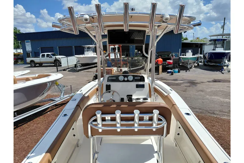 Slide: The Image of 2026 Pioneer 202 Islander boat interior with rod holders and control panel, parked outdoors. - 40