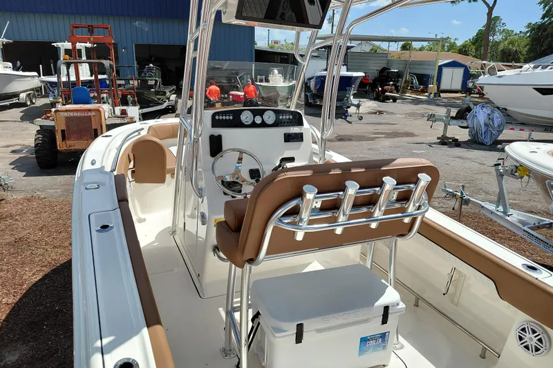 Slide: The Image of 2026 Pioneer 202 Islander boat interior with helm, seating, and rod holders in a marina setting. - 41