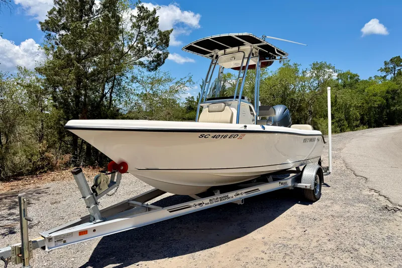 Slide: The Image of 2023 Key West 189 FS boat on trailer, parked on a sunny road with trees. - 34