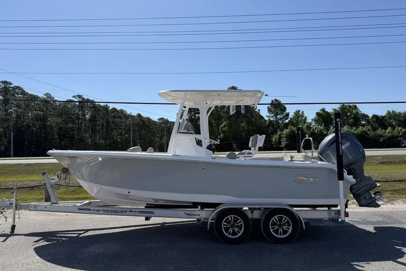 Slide: The Image of 2024 Sea Hunt Ultra 219 boat on trailer, parked outdoors under clear blue sky. - 2