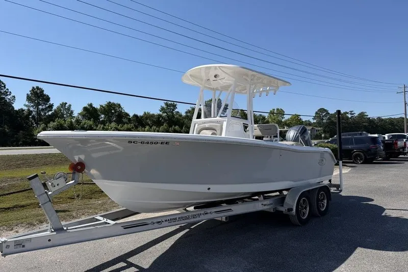 Slide: The Image of 2024 Sea Hunt Ultra 219 boat on trailer, parked outdoors under clear blue sky. - 4