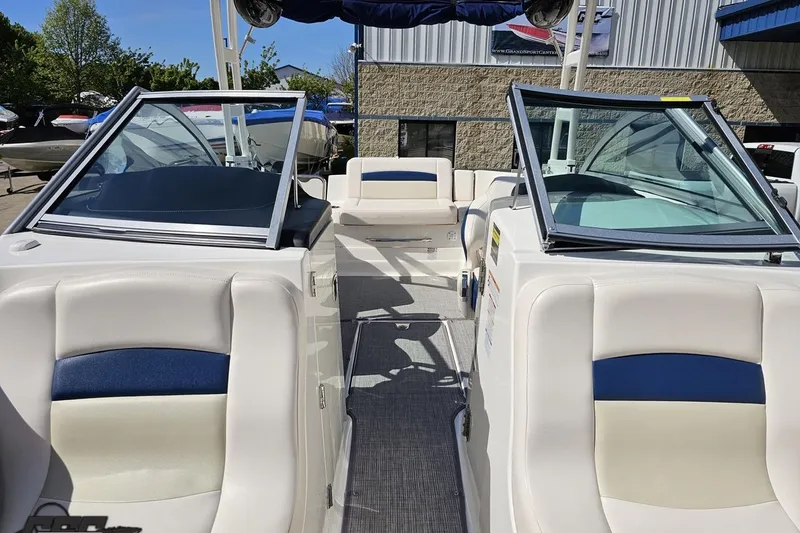 Slide: The Image of 2016 Chaparral 244 Sunesta boat interior with white and blue seating, docked outdoors. - 101