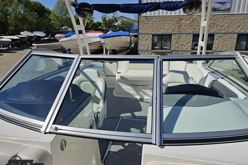 Slide: The Image of 2016 Chaparral 244 Sunesta boat interior with seating and windshield, parked outdoors. - 102