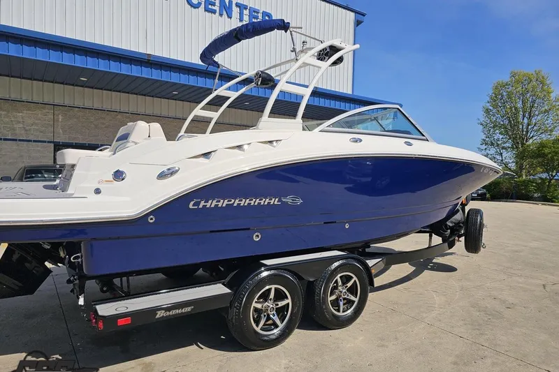 Slide: The Image of 2016 Chaparral 244 Sunesta boat on trailer, blue and white, parked outdoors. - 11