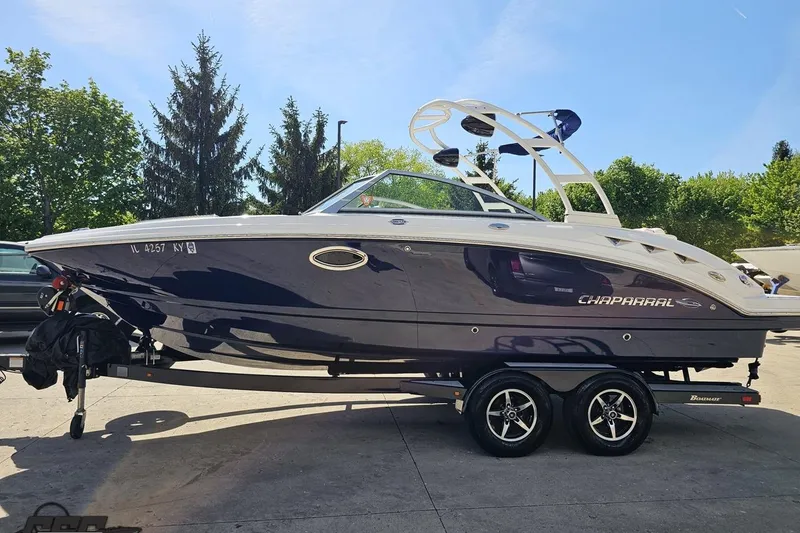Slide: The Image of 2016 Chaparral 244 Sunesta boat on trailer, parked outdoors with trees in background. - 25