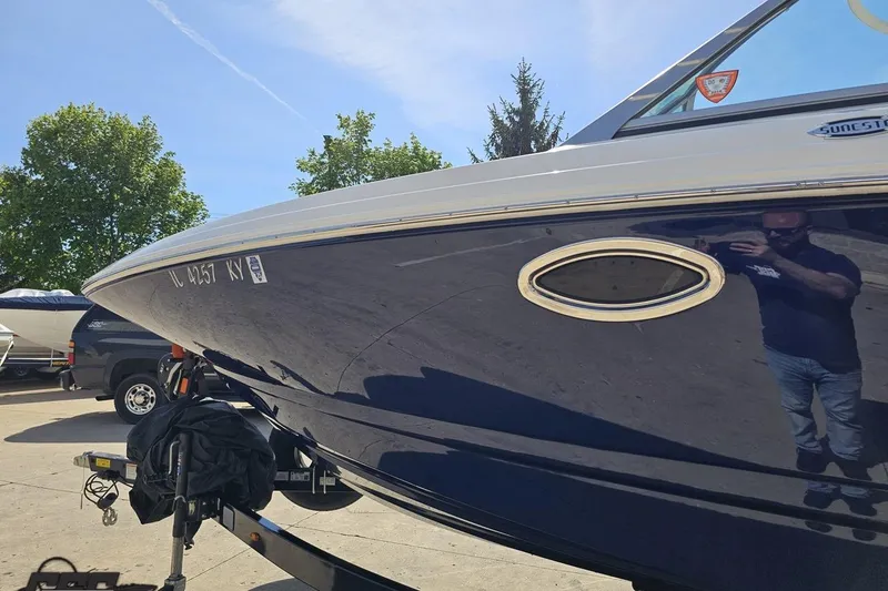 Slide: The Image of 2016 Chaparral 244 Sunesta boat on trailer, reflecting sunlight, with trees in the background. - 26