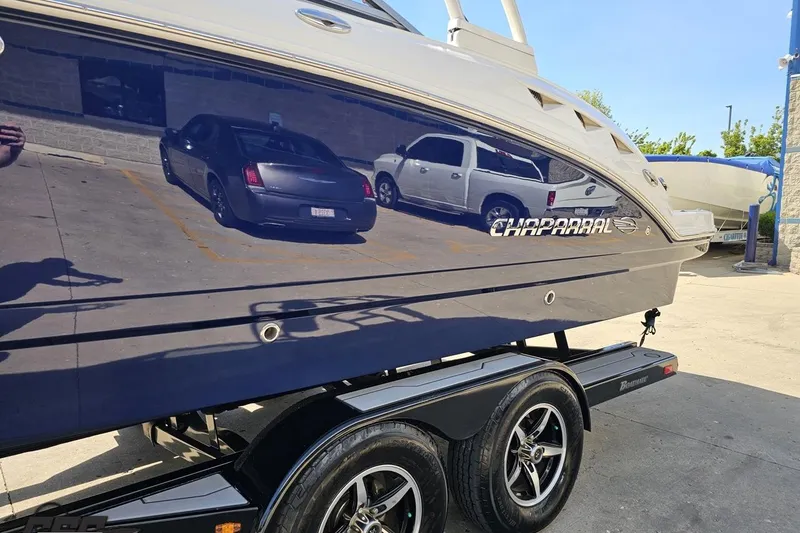 Slide: The Image of 2016 Chaparral 244 Sunesta boat on trailer, reflecting parked cars in a sunny lot. - 27
