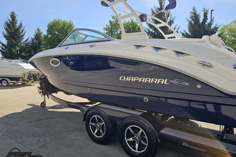 Slide: The Image of 2016 Chaparral 244 Sunesta boat on trailer, parked outdoors, with trees in background. - 31