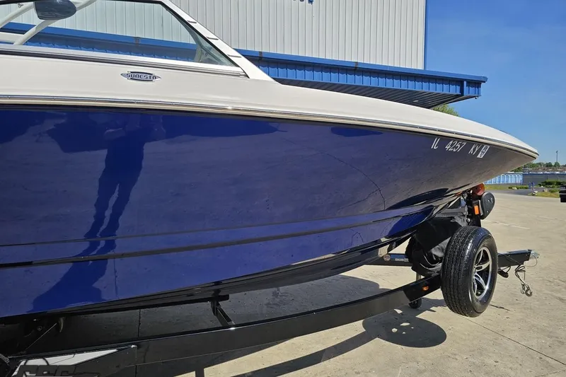 Slide: The Image of 2016 Chaparral 244 Sunesta boat on trailer, blue hull, parked outdoors. - 5