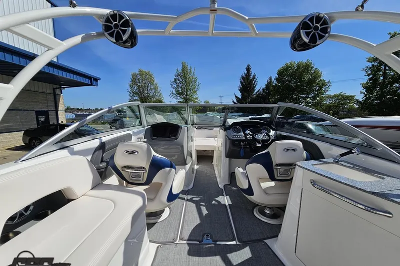 Slide: The Image of 2016 Chaparral 244 Sunesta boat interior with seating and dashboard, under clear blue sky. - 56