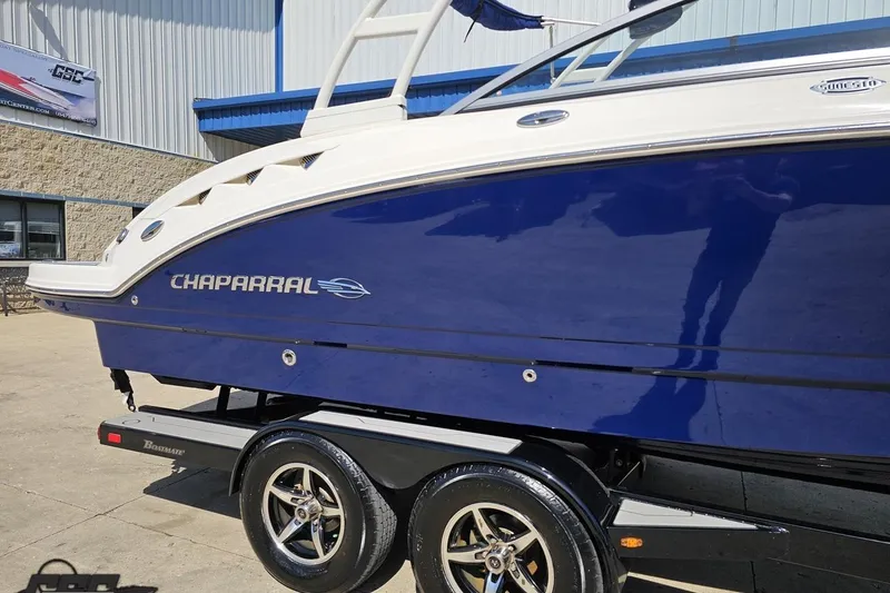 Slide: The Image of 2016 Chaparral 244 Sunesta boat on trailer, blue and white exterior, parked outdoors. - 6
