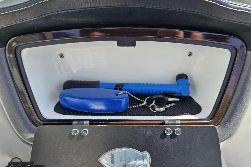 Slide: The Image of Storage compartment in 2016 Chaparral 244 Sunesta boat with keys and blue flashlight. - 80