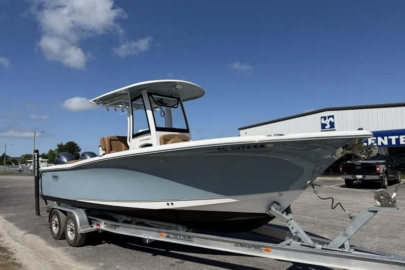 The Image of 2024 Sea Hunt Ultra 265 SE boat on trailer, parked outdoors under blue sky. - 1