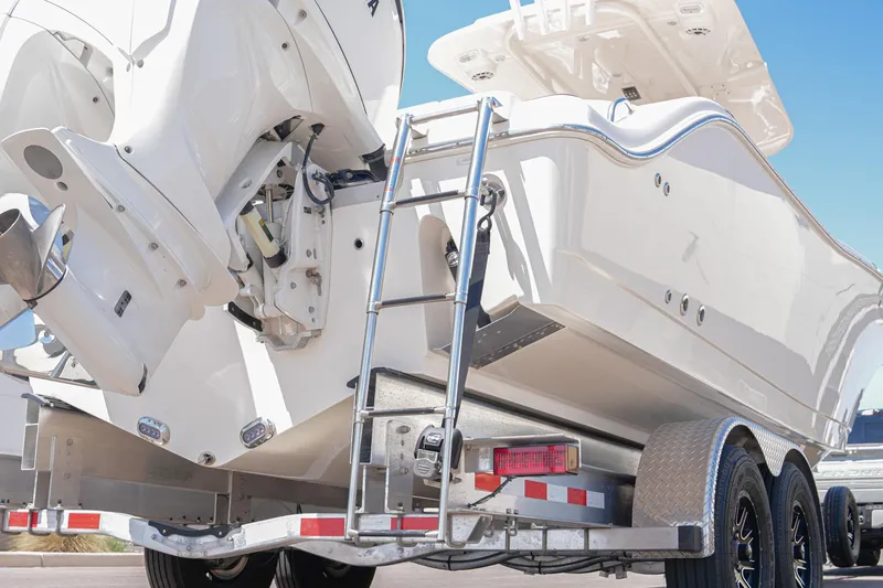 Slide: The Image of 2024 NauticStar 292 Legacy boat on trailer, showcasing rear view and ladder. - 13