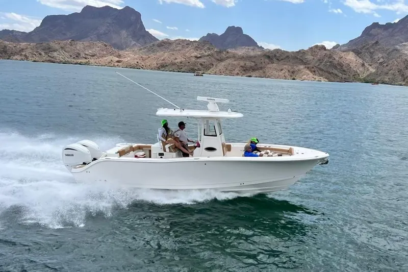 Slide: The Image of 2024 NauticStar 292 Legacy boat cruising on a scenic lake with mountainous backdrop. - 15