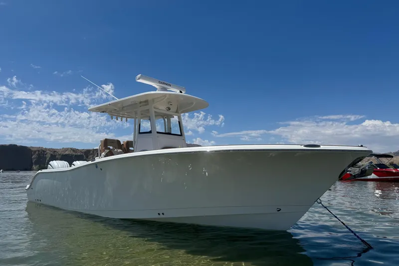 Slide: The Image of 2024 NauticStar 292 Legacy boat anchored in clear water under a blue sky. - 16