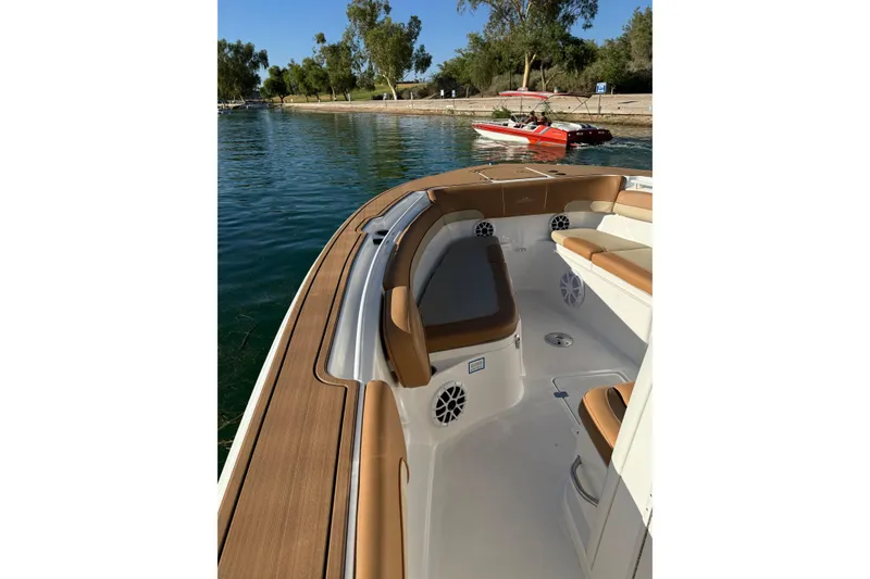 Slide: The Image of 2024 NauticStar 292 Legacy boat interior with tan seating, docked by a scenic shoreline. - 23