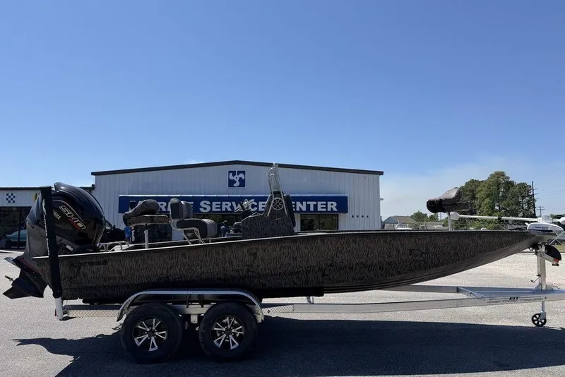 Slide: The Image of 2026 Xpress H22B Bay boat on trailer outside marine service center. - 11