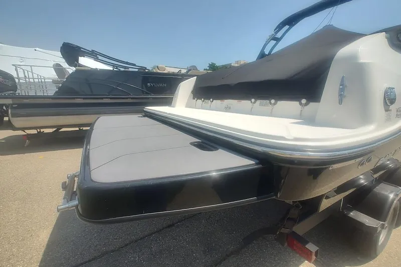 Slide: The Image of 2023 Bayliner DX 2250 boat rear view with swim platform in a marina setting. - 4