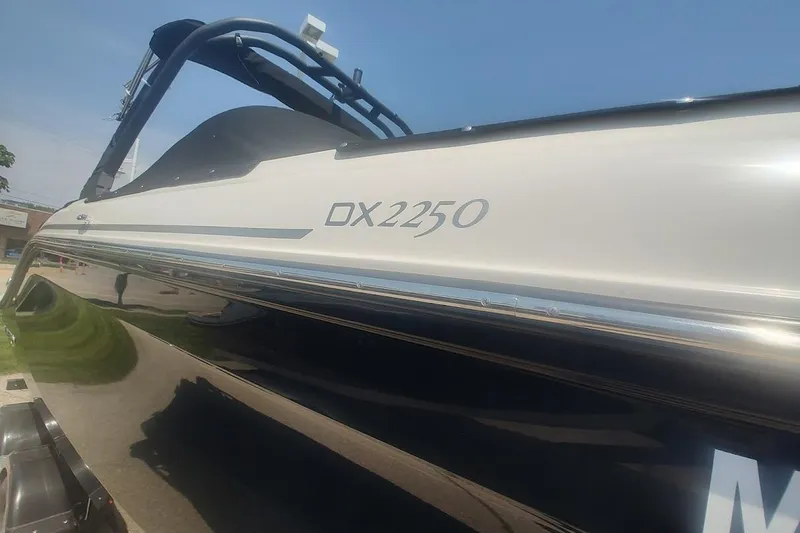 Slide: The Image of 2023 Bayliner DX 2250 boat side view with sleek design and branding. - 6