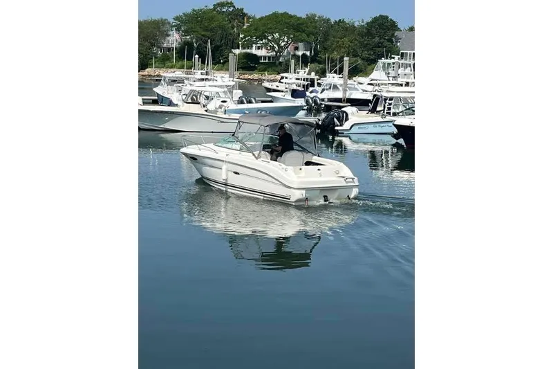 Slide: The Image of 2004 Sea Ray 215 Weekender boat cruising in a marina with other vessels. - 1