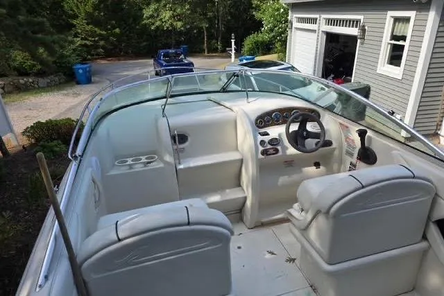 Slide: The Image of 2004 Sea Ray 215 Weekender boat interior with steering wheel and seating, parked near a garage. - 4