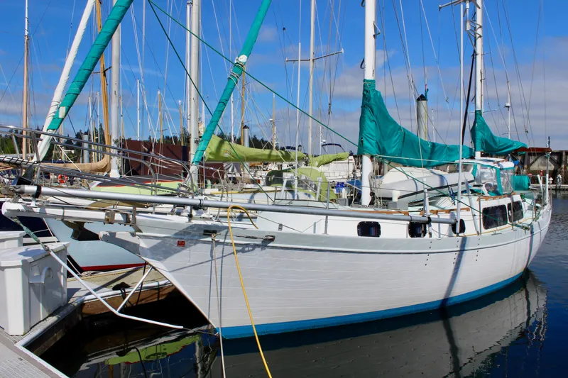 The Image of 1975 Downeast 38 sailboat docked in a marina under a clear blue sky. - 0