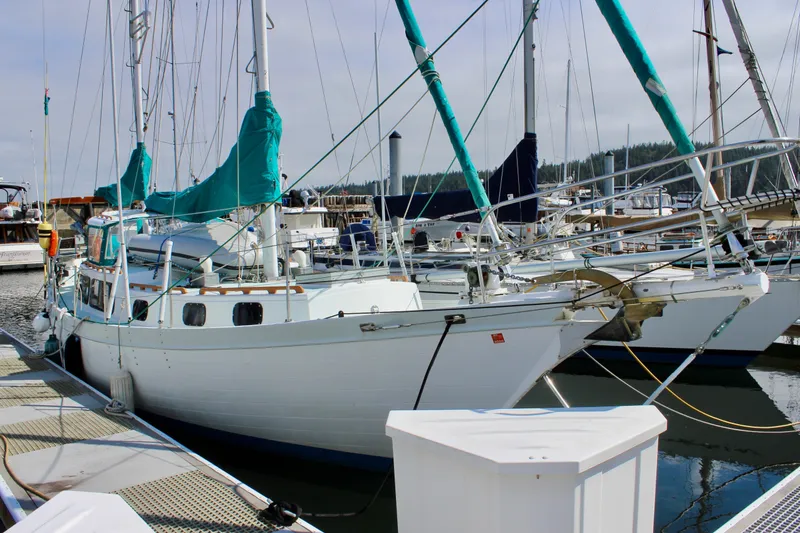 Slide: The Image of 1975 Downeast 38 sailboat docked at a marina, featuring teal sail covers. - 1