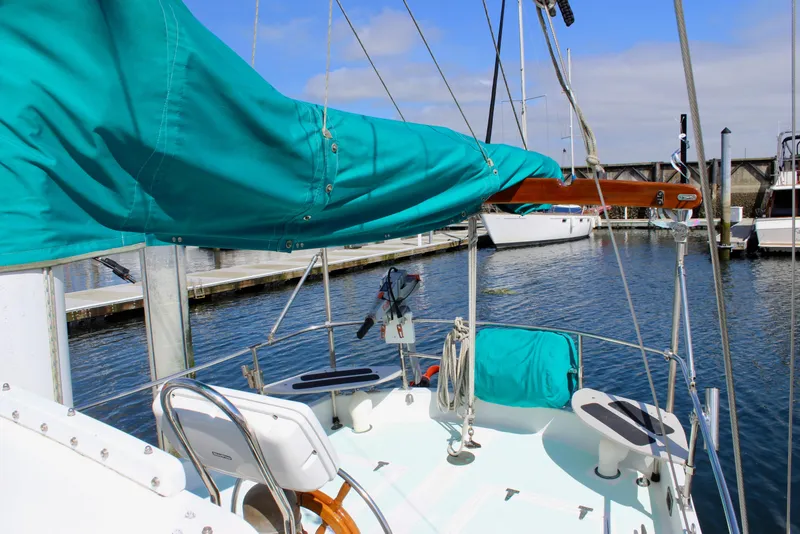 Slide: The Image of 1975 Downeast 38 sailboat docked, featuring teal sail cover and marina backdrop. - 15