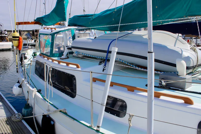 Slide: The Image of 1975 Downeast 38 sailboat docked with dinghy on deck, featuring teal accents. - 2