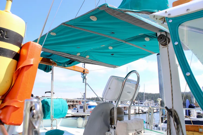 Slide: The Image of 1975 Downeast 38 sailboat with teal canopy and lifebuoy, docked at marina. - 28