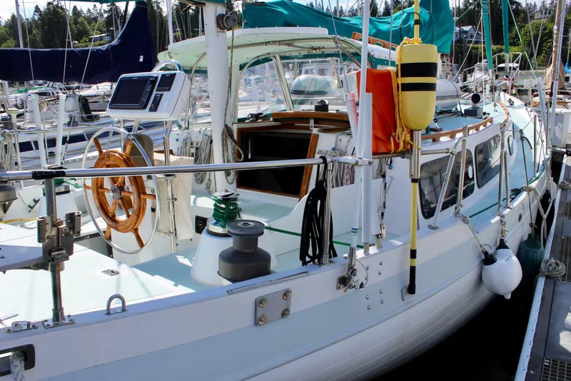 Slide: The Image of 1975 Downeast 38 sailboat docked at marina, featuring wooden steering wheel and nautical equipment. - 4