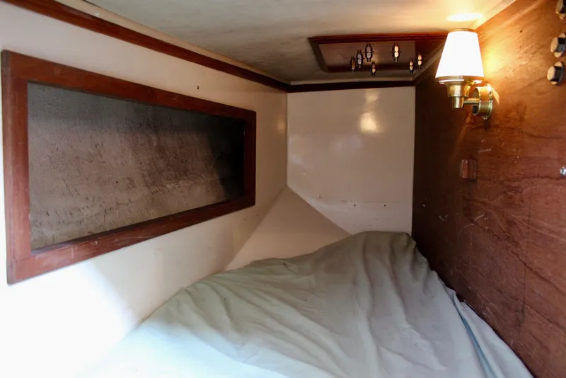 Slide: The Image of 1975 Downeast 38 boat cabin interior with bed, wooden paneling, and wall lamp. - 46
