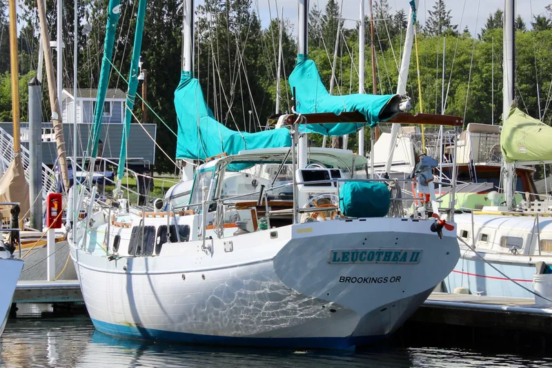 Slide: The Image of 1975 Downeast 38 sailboat docked in marina, featuring teal covers and lush surroundings. - 5